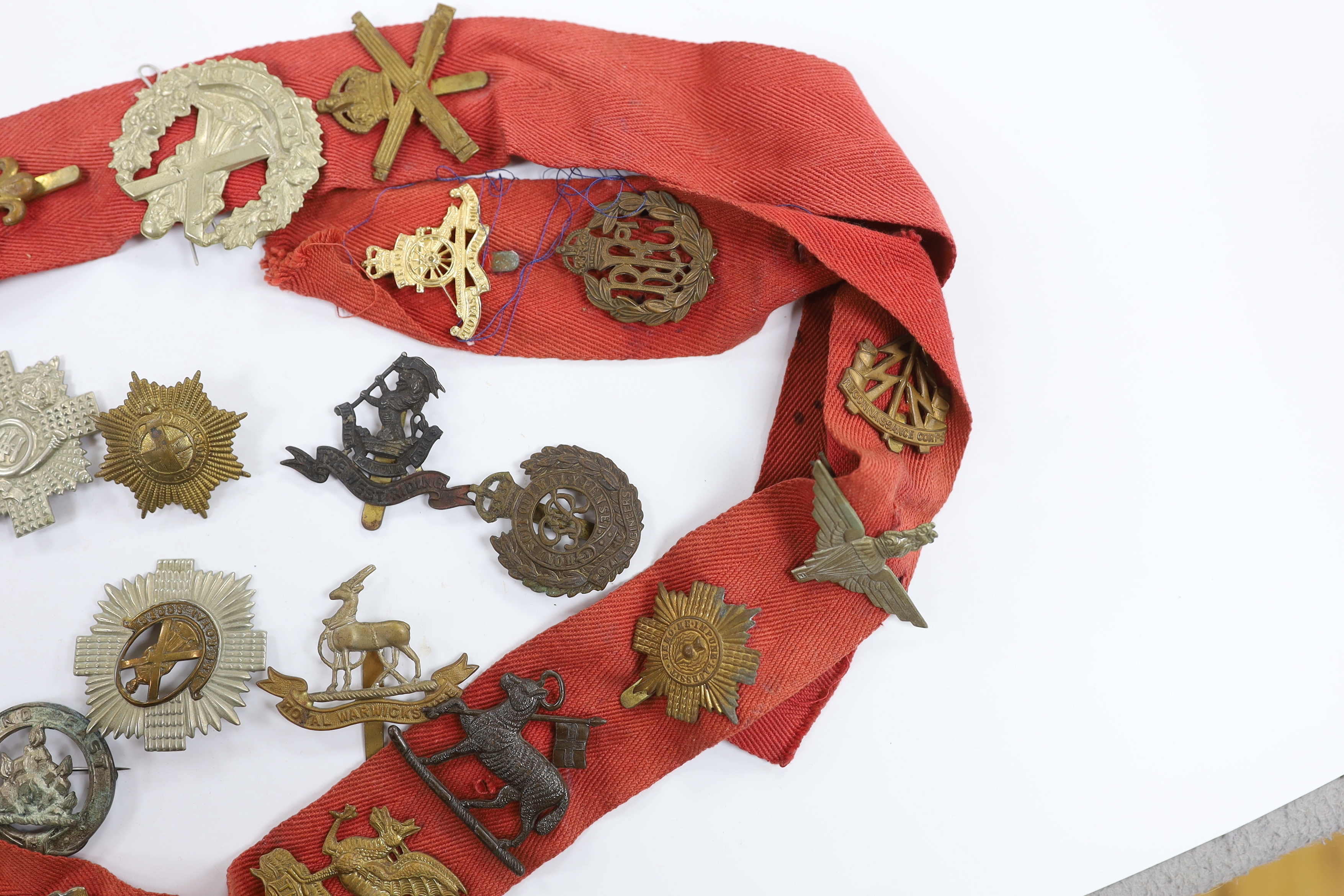 Thirty-two military cap badges, including; The Devonshire Reg., The Buffs, RFC, Royal Artillery, The Royal Sussex Reg. Royal Warwickshire Reg., Cornwall, etc.